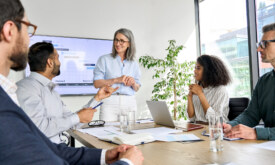 International executive team people having board meeting discussing project results. Diverse employees group working with senior leader brainstorming in office meeting room at presentation training.