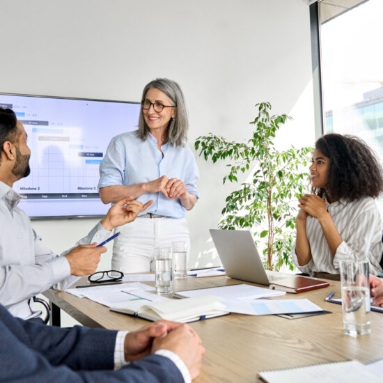 International executive team people having board meeting discussing project results. Diverse employees group working with senior leader brainstorming in office meeting room at presentation training.